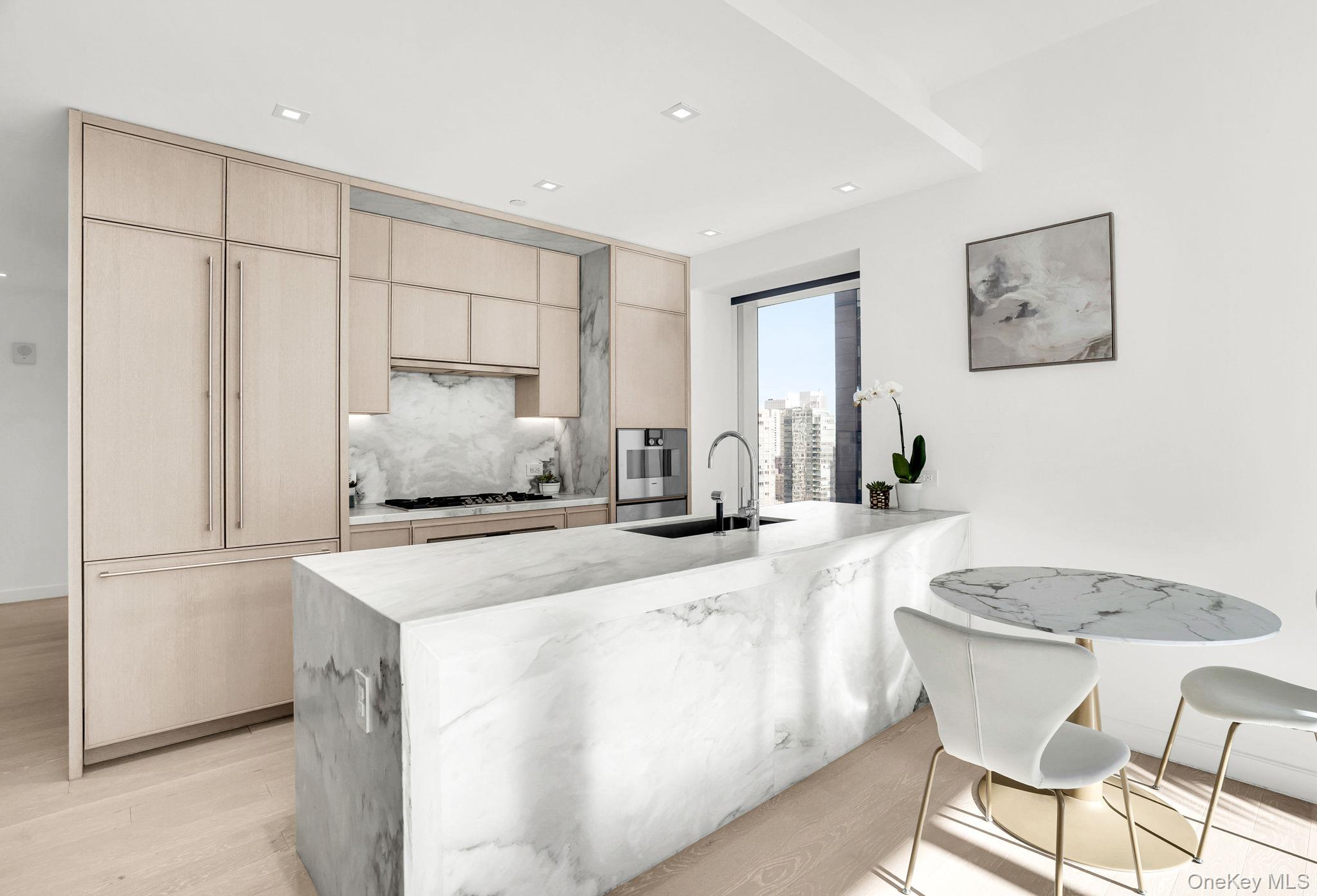 138 East 50th Street, Unit 26C Manhattan, NY 10022 - Photo 15 of 31 a kitchen with stainless steel appliances granite countertop a sink a stove a refrigerator a white table and chairs