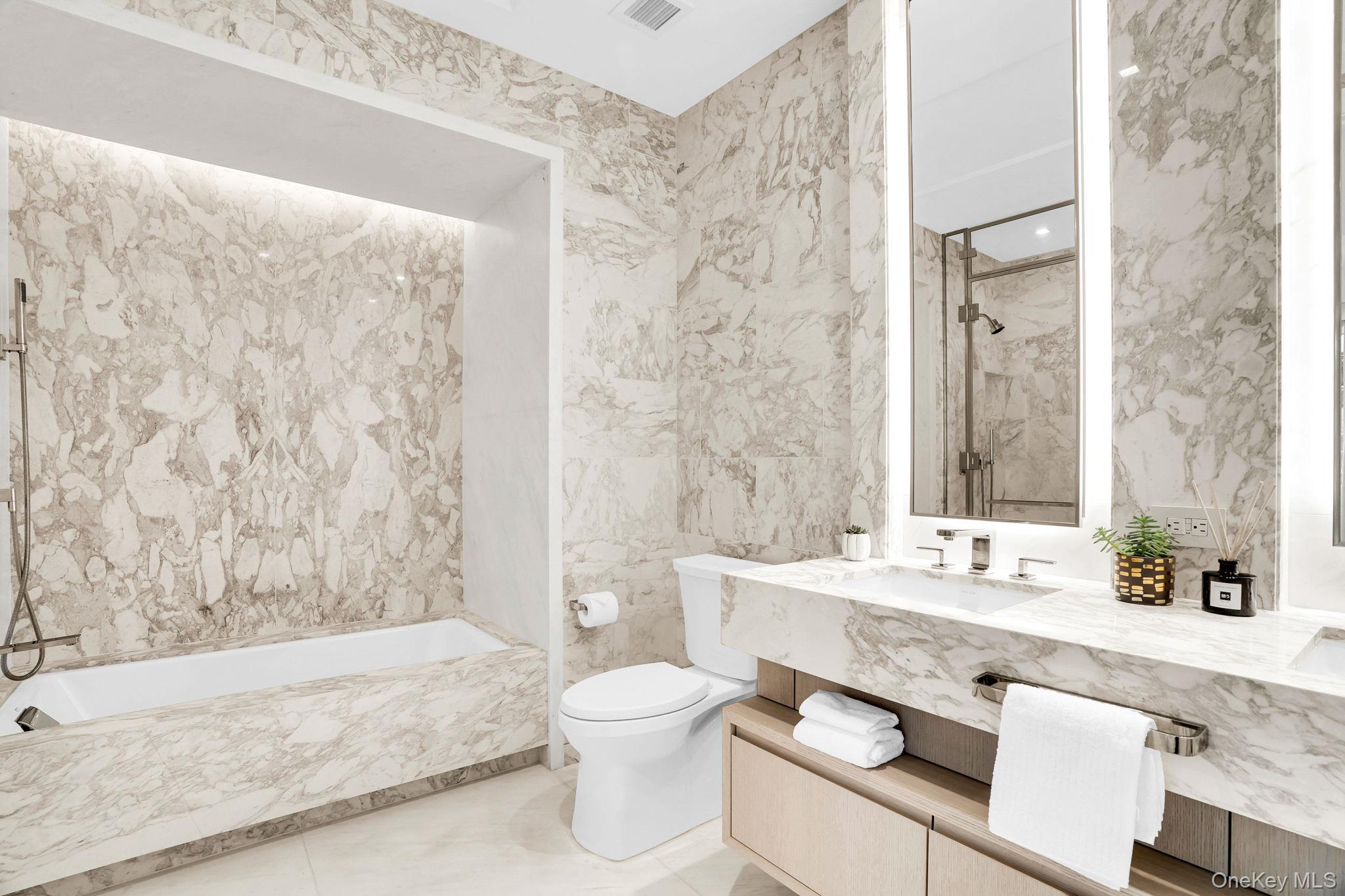 138 East 50th Street, Unit 26C Manhattan, NY 10022 - Photo 20 of 31 a bathroom with a granite countertop bathtub sink vanity mirror and toilet