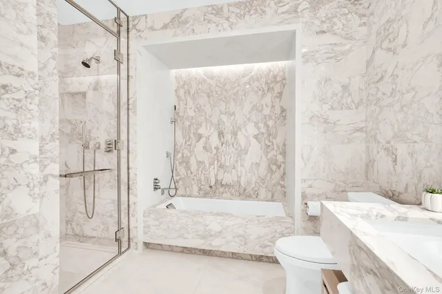 a bathroom with a granite countertop bathtub shower sink and toilet