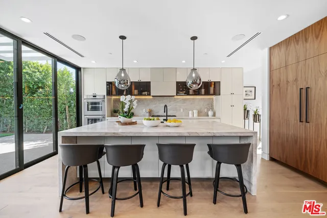 a kitchen with stainless steel appliances granite countertop a dining table chairs and granite counter tops
