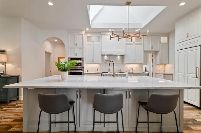 a kitchen with granite countertop a counter space chairs cabinets and appliances