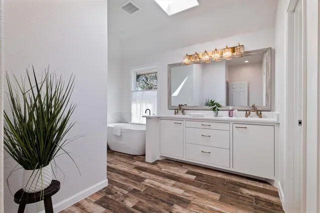 a bathroom with a sink a mirror and a potted plant