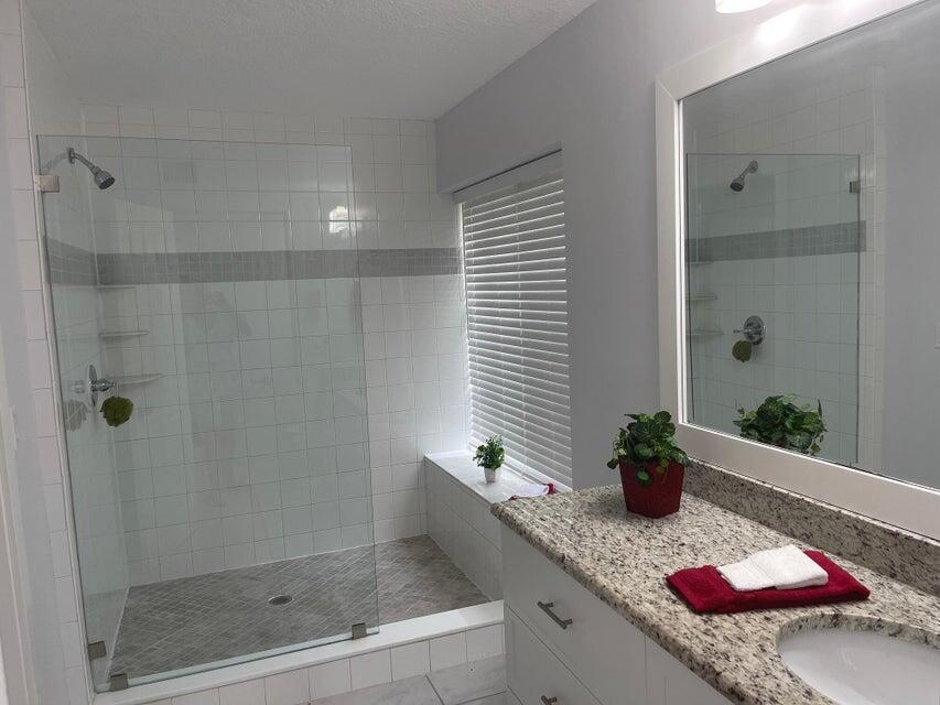 639 Executive Center Drive, Unit O107 West Palm Beach, FL 33401 - Photo 16 of 21 a bathroom with a granite countertop sink a potted plant and shower