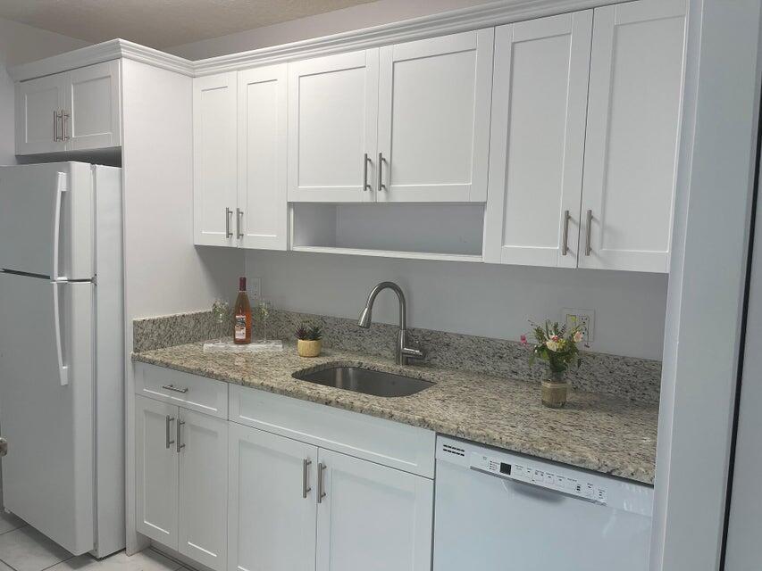 639 Executive Center Drive, Unit O107 West Palm Beach, FL 33401 - Photo 4 of 21 a kitchen with white cabinets and a sink