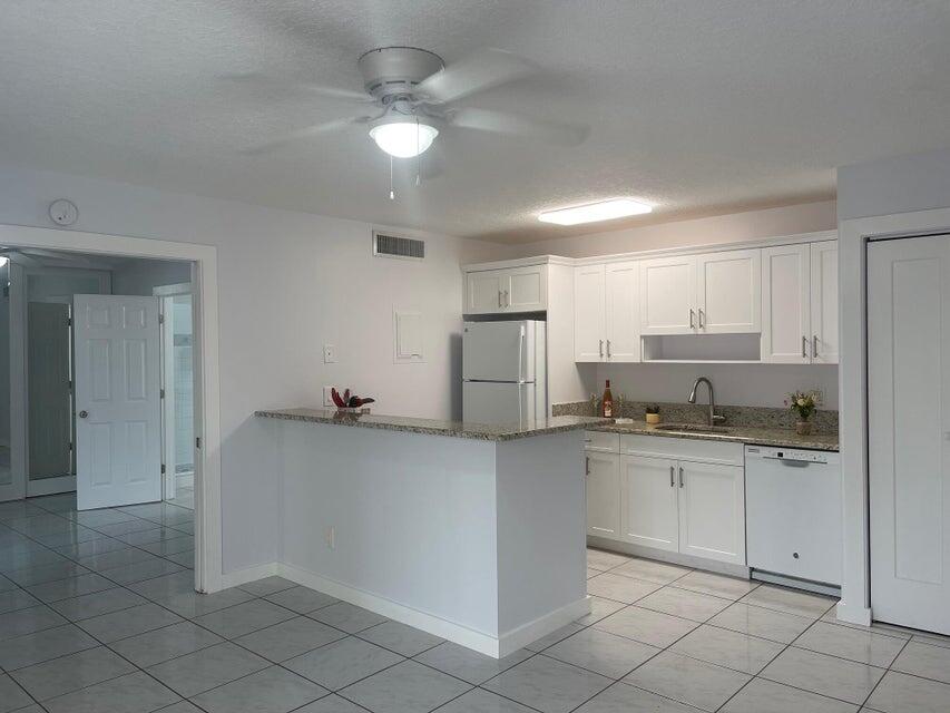 639 Executive Center Drive, Unit O107 West Palm Beach, FL 33401 - Photo 5 of 21 a kitchen with white cabinets and stainless steel appliances