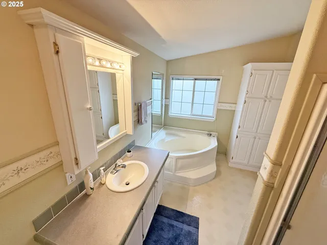 a spacious bathroom with a tub sink and mirror
