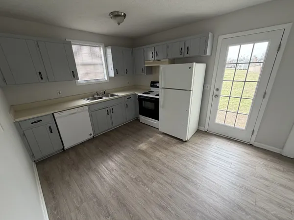 a kitchen with a refrigerator a sink and dishwasher with wooden floors