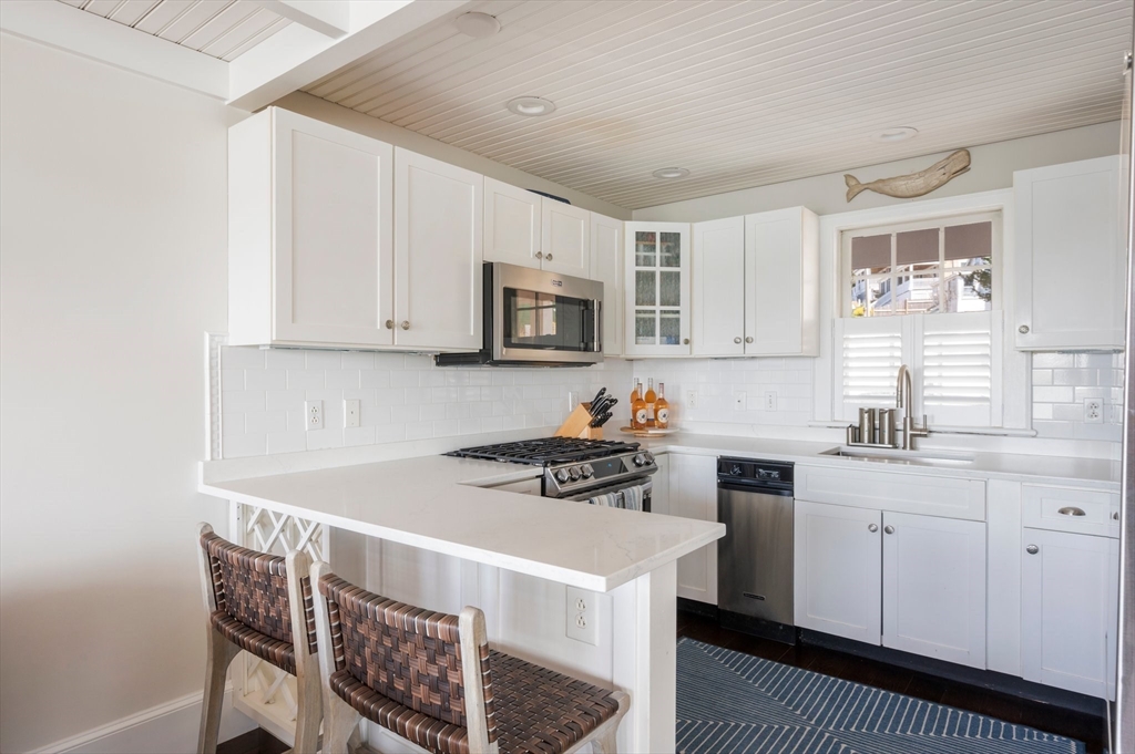 87 Bay Street Hull, MA 02045 - Photo 10 of 30 a kitchen with stainless steel appliances a sink a stove a microwave a refrigerator cabinets and a window