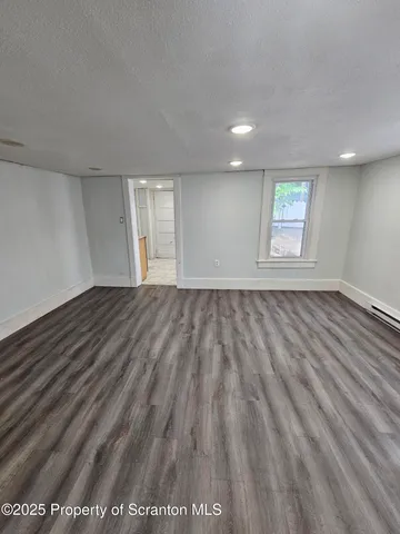 a view of an empty room with kitchen view and a window