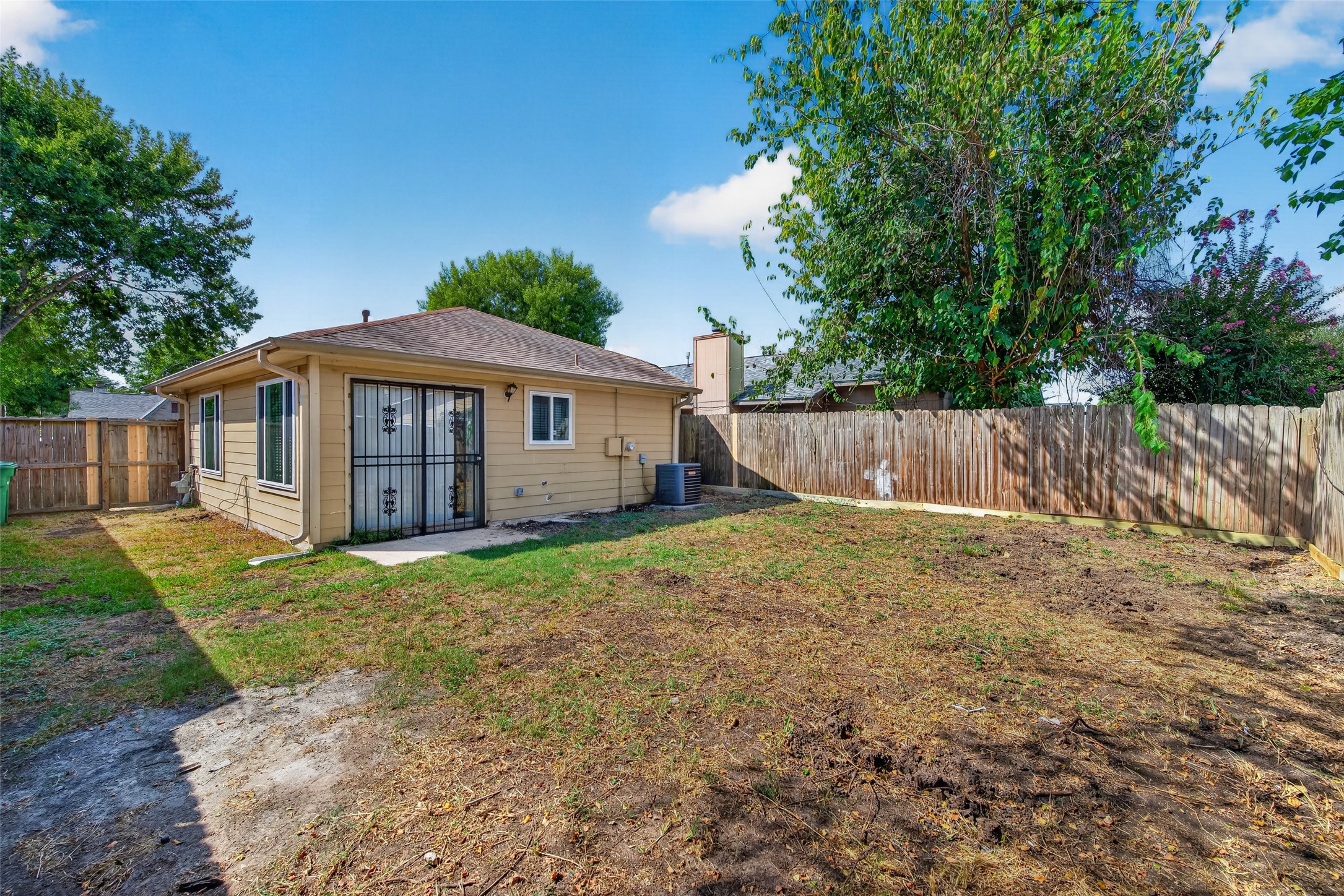 16203 Beck Ridge Drive Houston, TX 77053 - Photo 29 of 29 Backyard with a spacious patio area, perfect for outdoor activities, surrounded by mature trees and a wooden fence for privacy.