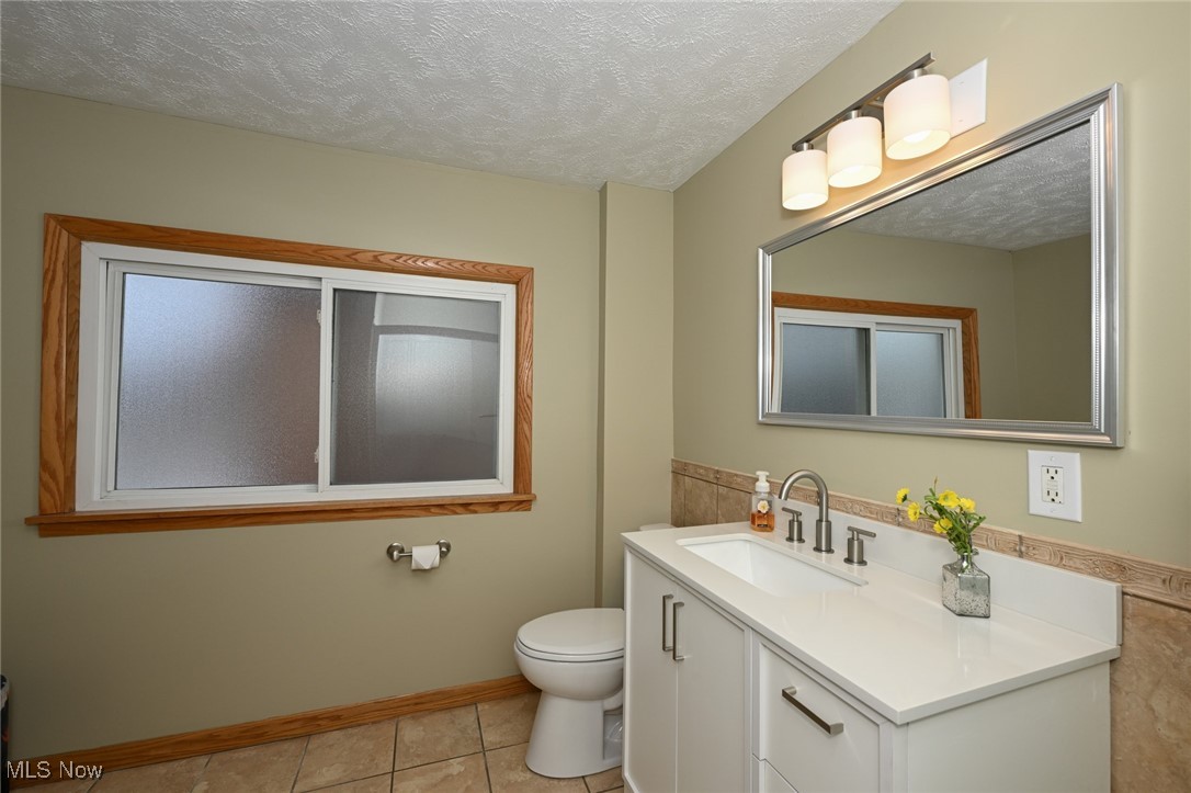 1164 Copley Road Akron, OH 44320 - Photo 33 of 50 Bathroom featuring a textured ceiling, toilet, vanity, baseboards, and tile patterned floors