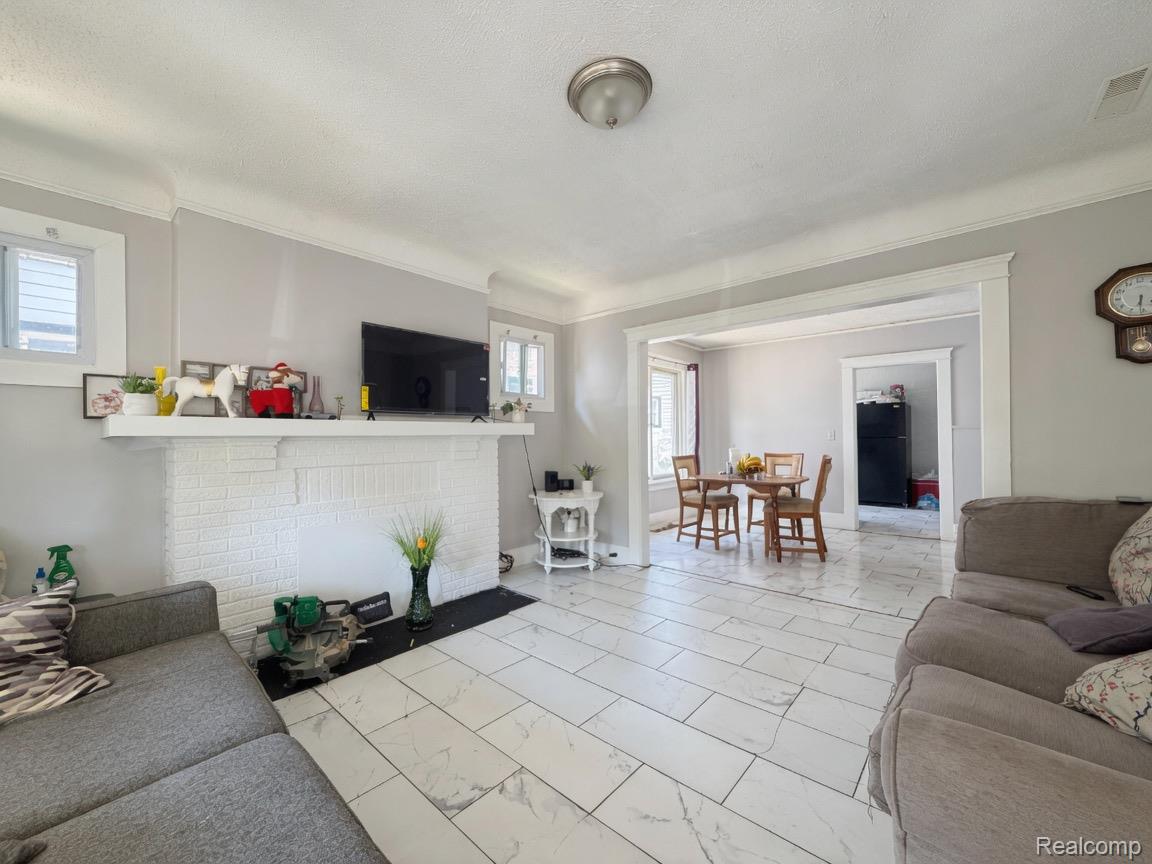 9940 Manor Detroit, MI 48204 - Photo 5 of 16 Spacious interior featuring wide plank tile flooring, a white brick fireplace, and crown molding