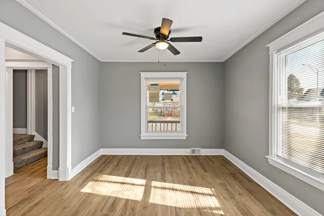a view of empty room with wooden floor and fan