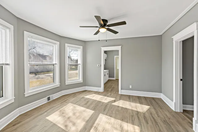 a view of an empty room with a window and wooden floor