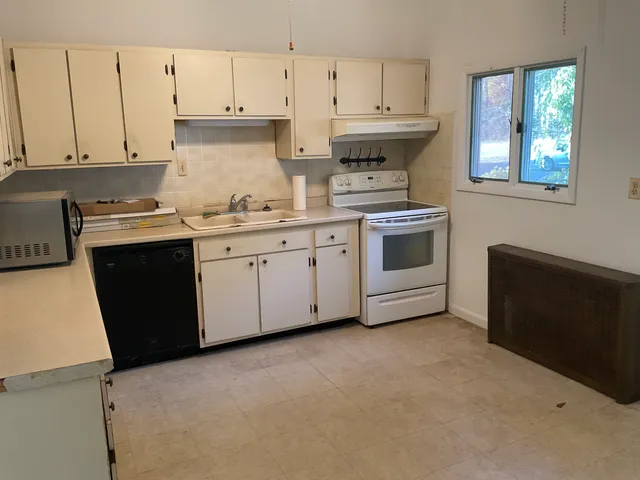 a kitchen with granite countertop white cabinets and white appliances