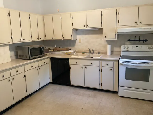 a kitchen with granite countertop white cabinets and white appliances