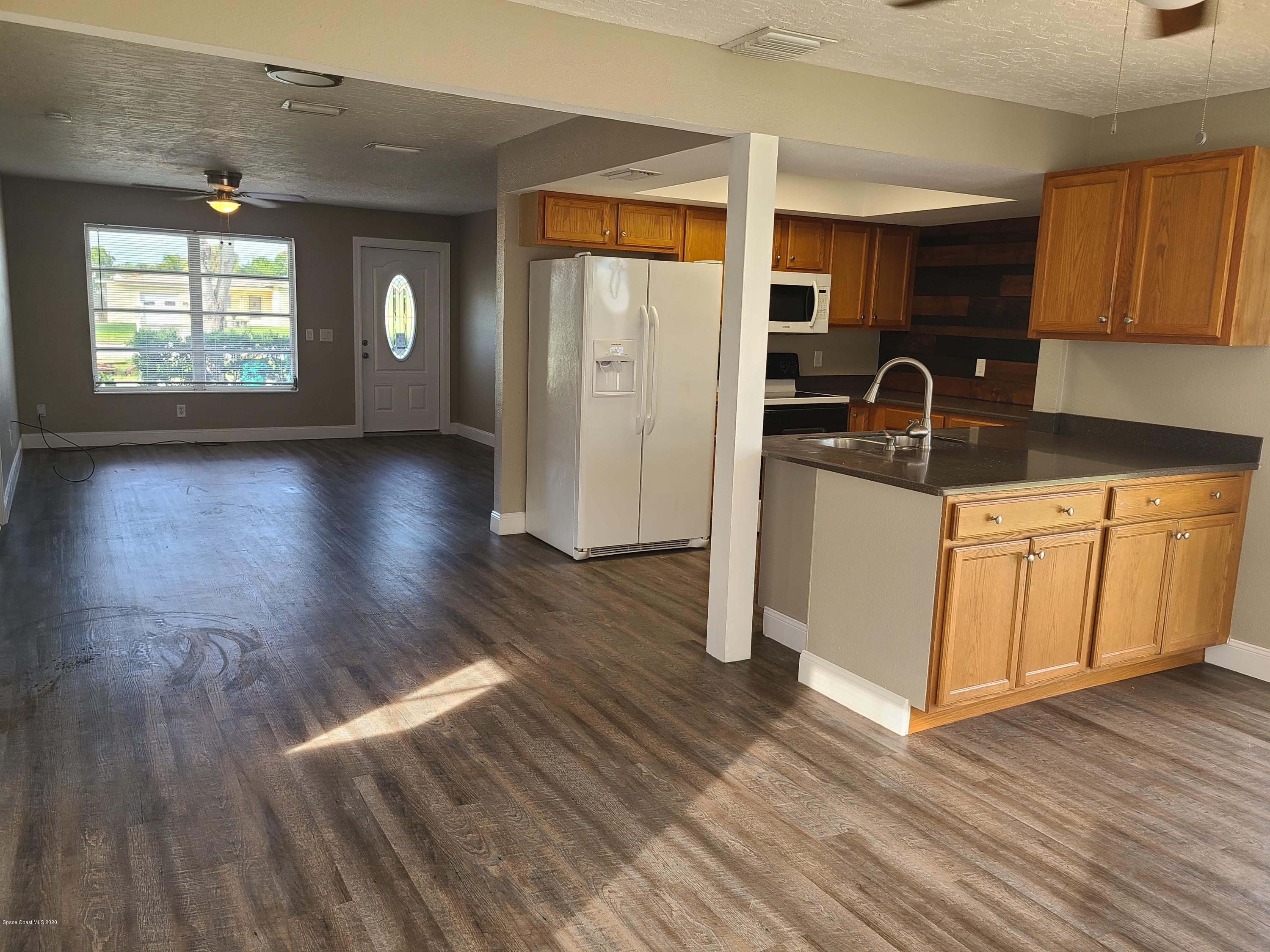 1705 Sarno (access) Road Melbourne, FL 32935 - Photo 13 of 32 a kitchen with granite countertop a stove a sink and a refrigerator