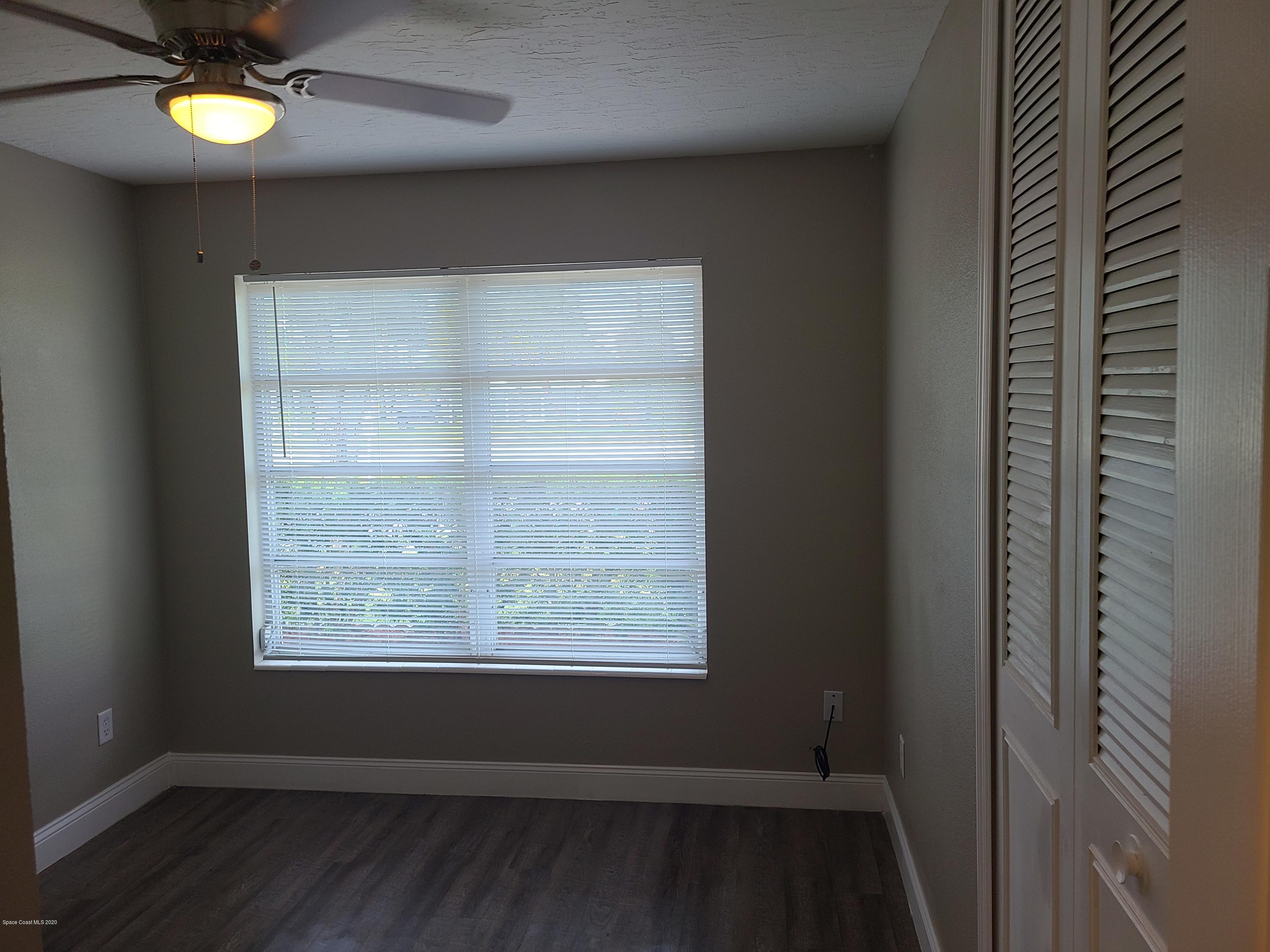 1705 Sarno (access) Road Melbourne, FL 32935 - Photo 21 of 32 an empty room with wooden floor and windows