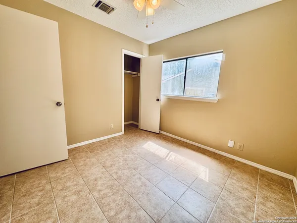 a view of an empty room with window and chandelier fan