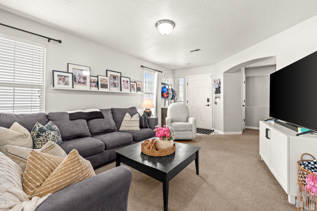 174 Rockey Park Lane, Unit 34 Draper, UT 84020 - Photo 3 of 20 Living room featuring arched walkways, light carpet, and a textured ceiling
