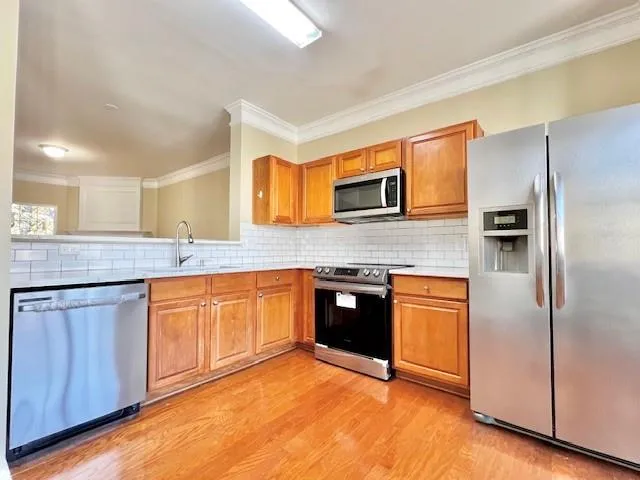 a large kitchen with granite countertop stainless steel appliances and wooden cabinets