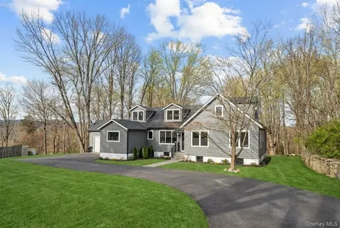 a front view of a house with a garden and trees