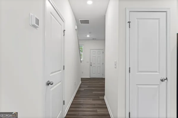 a view of a hallway with wooden floor and a bathroom