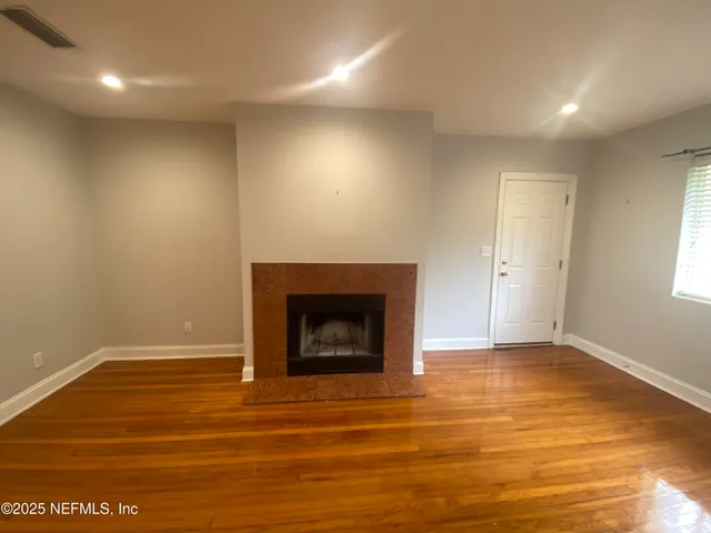 an empty room with wooden floor and a fireplace