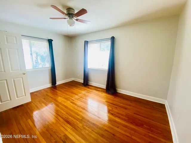 an empty room with wooden floor and windows