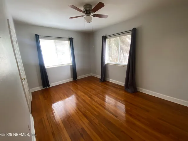 a view of empty room with wooden floor and fan