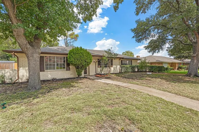 a view of a house with a yard and large tree