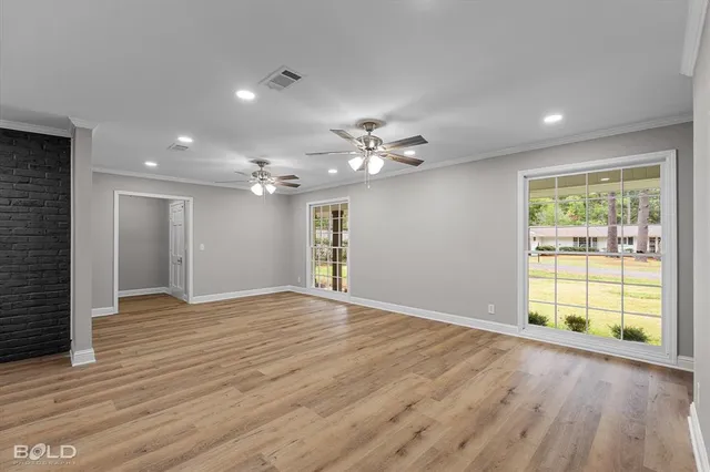 a view of an empty room with a window and wooden floor