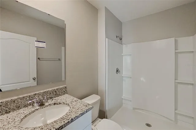 a bathroom with a granite countertop sink toilet and shower