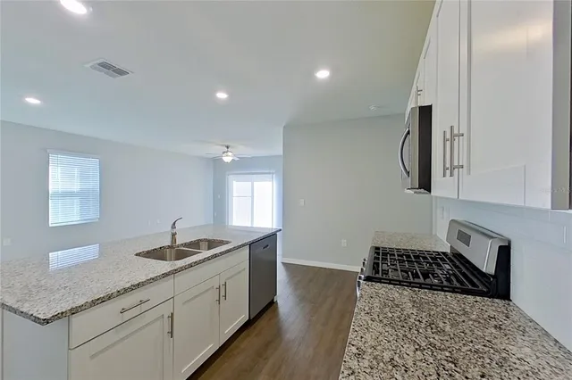 a kitchen with stainless steel appliances granite countertop a sink stove and cabinets