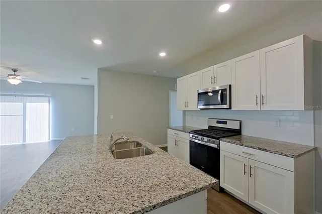 a kitchen with stainless steel appliances granite countertop a sink stove and microwave