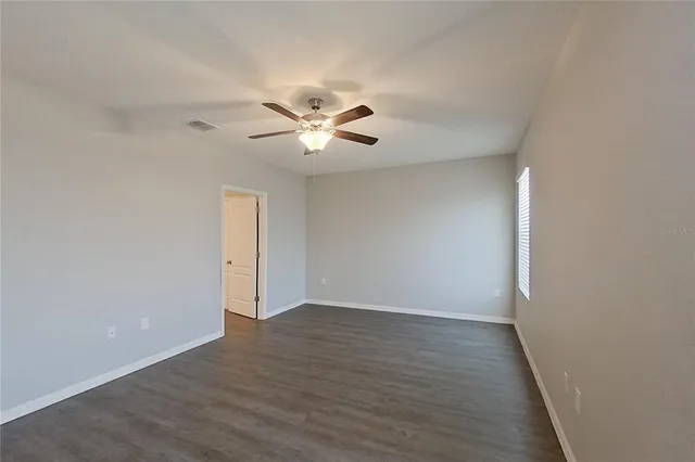an empty room with wooden floor and a ceiling fan