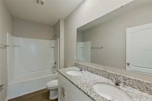 a bathroom with a granite countertop sink a toilet and bathtub