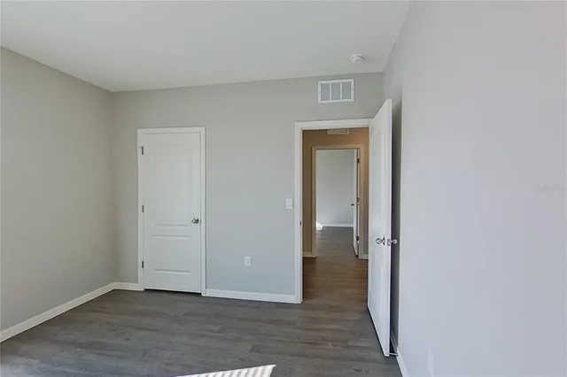 a view of an empty room with wooden floor and closet