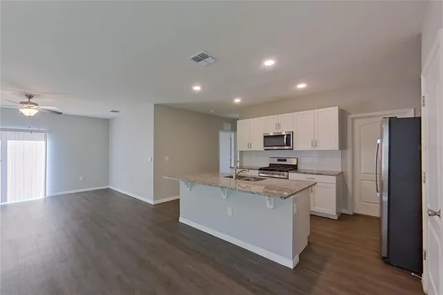 a kitchen with stainless steel appliances kitchen island granite countertop a stove and a refrigerator