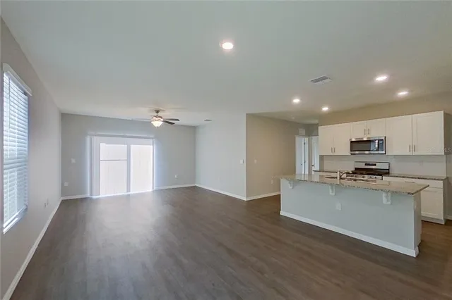 a view of kitchen with kitchen island wooden floors and stainless steel appliances