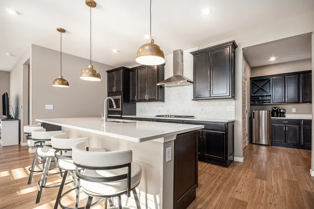 a kitchen with stainless steel appliances granite countertop a sink a stove a refrigerator and island with wooden floor