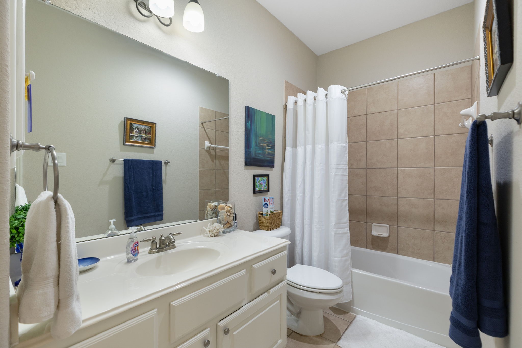 20410 Misty Crossing Lane Spring, TX 77379 - Photo 26 of 50 This bathroom is located by the upfront bedroom and features a large mirror, a light fixtures and a spacious vanity with ample storage. It includes a bathtub with tiled walls, complemented by tasteful decor and a neutral color palette for a soothing atmosphere.