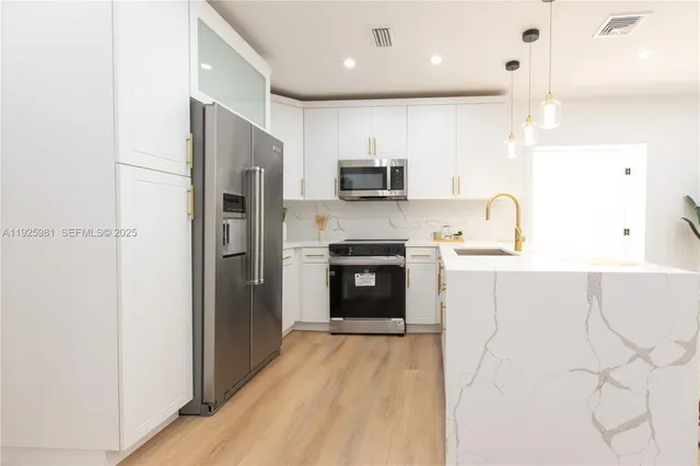 a kitchen with kitchen island a counter top space stainless steel appliances and cabinets
