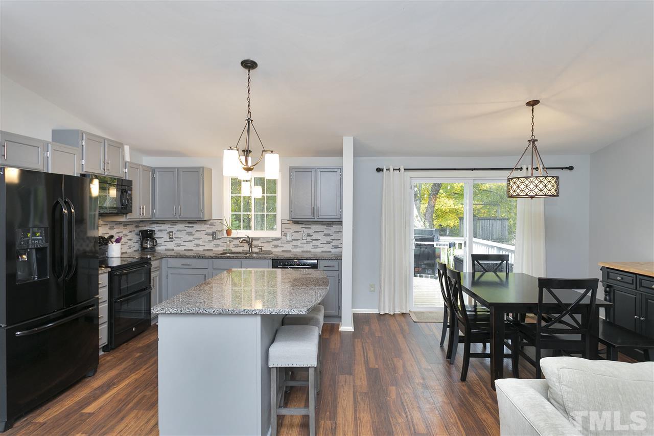 408 Electra Drive Cary, NC 27513 - Photo 6 of 25 a kitchen with kitchen island granite countertop a table chairs stove and refrigerator