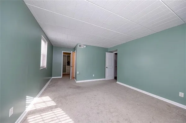 a view of an empty room with window and stairs