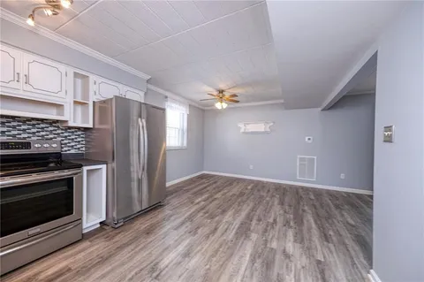 a view of a kitchen with a stove wooden cabinets and entryway