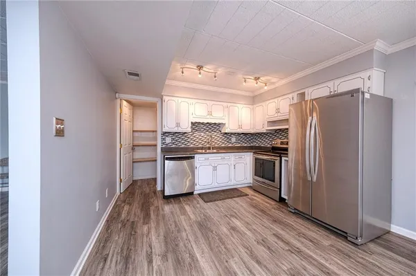 a kitchen with a refrigerator and white cabinets