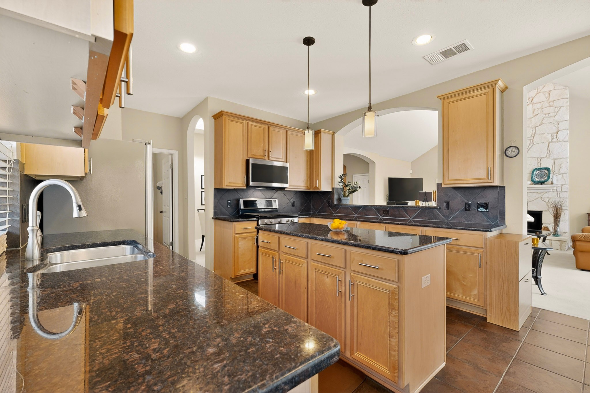905 Victoria Ridge Drive Pflugerville, TX 78660 - Photo 11 of 32 A well-appointed kitchen features rich granite countertops and modern appliances, flowing into an inviting living area.