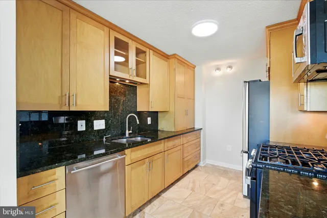 a kitchen with stainless steel appliances granite countertop a sink stove and refrigerator