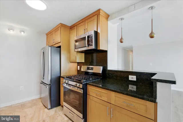 a kitchen with stainless steel appliances granite countertop a stove a refrigerator and a cabinets